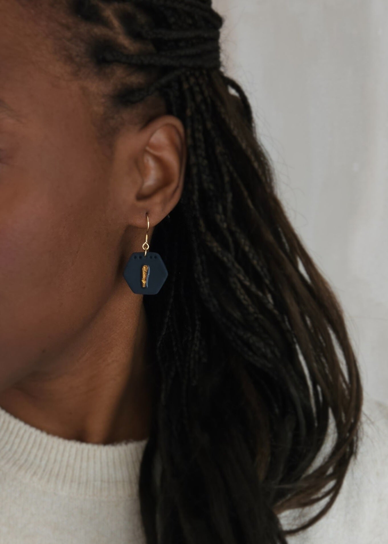 Le mannequin porte une paire de boucles d'oreilles Ambitieuse, coloris Bleu Nuit avec, au centre, une feuille d'or protégée par de la résine