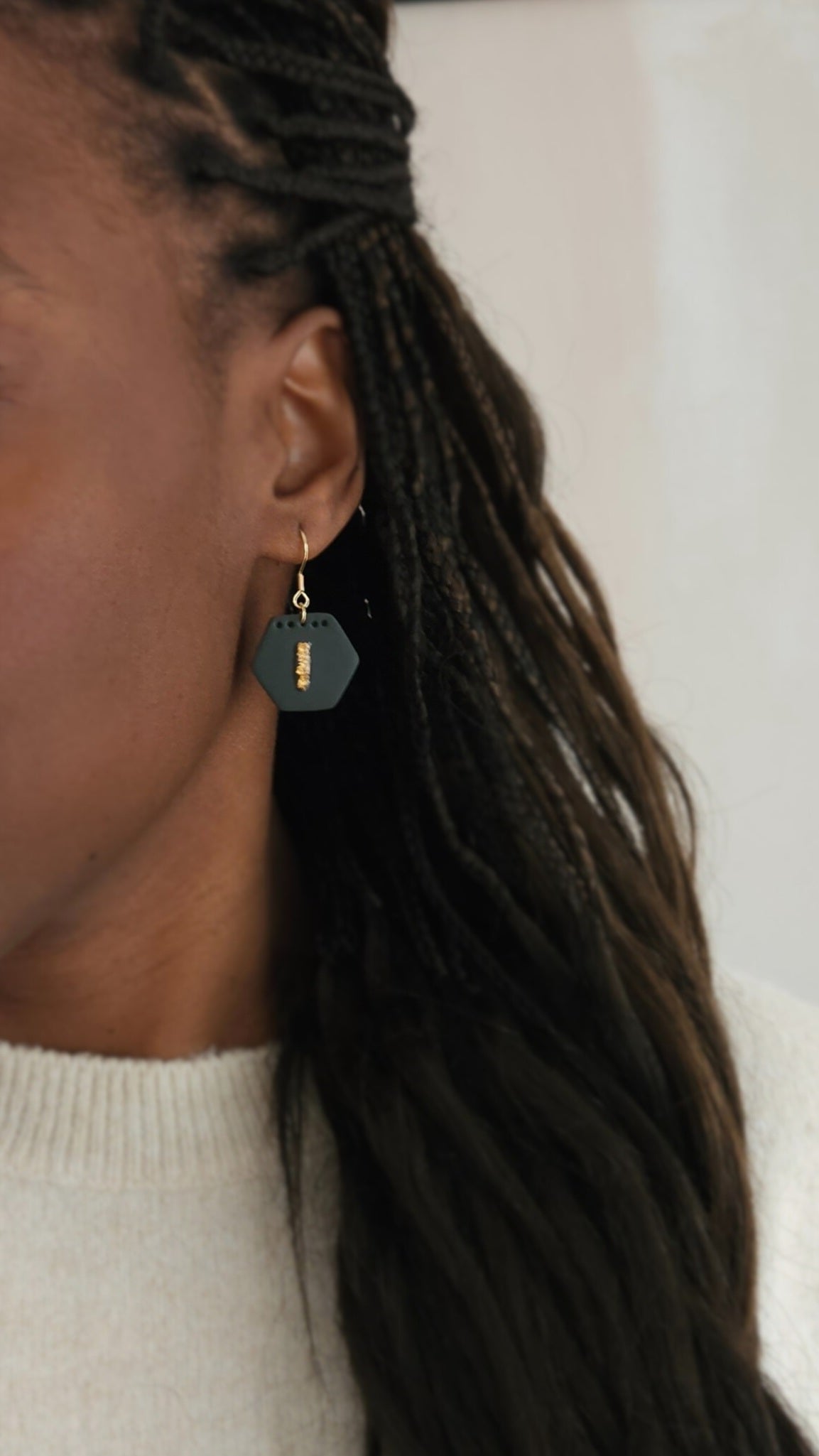 Le mannequin porte une paire de boucles d'oreilles Ambitieuse, coloris Vert profond avec, au centre, une feuille d'or protégée par de la résine