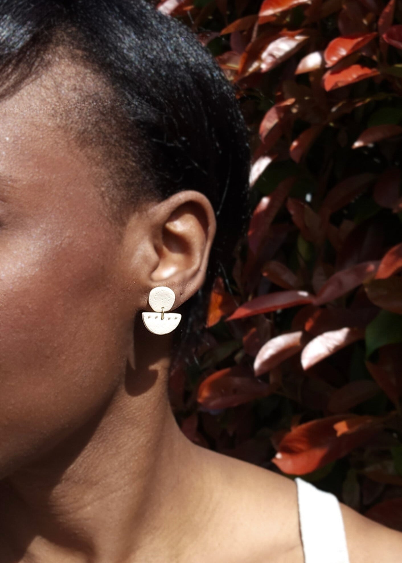 Le mannequin porte la paire de boucles d'oreilles Patiente dans son coloris sable 